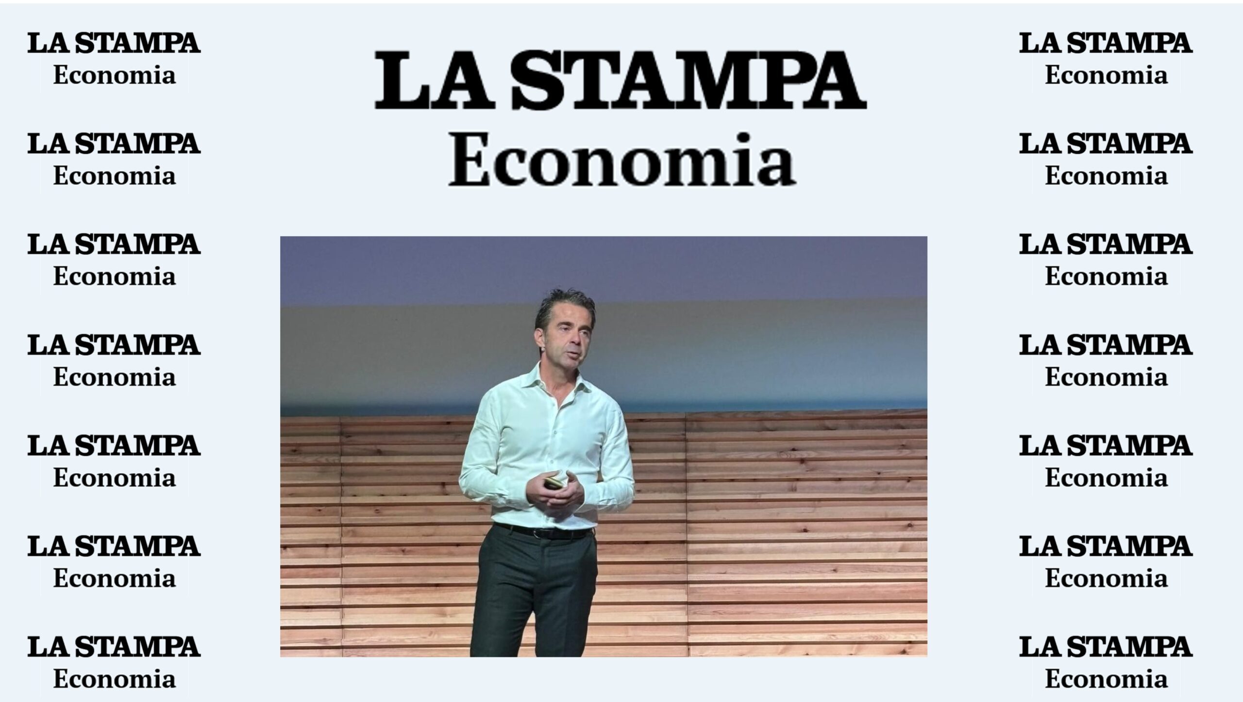 Un uomo in camicia bianca si trova su un palco di legno, con in mano un telecomando. Sullo sfondo è presente il logo de La Stampa Economia, ripetuto su entrambi i lati, a sottolineare l'evento del 22 ottobre 2025.