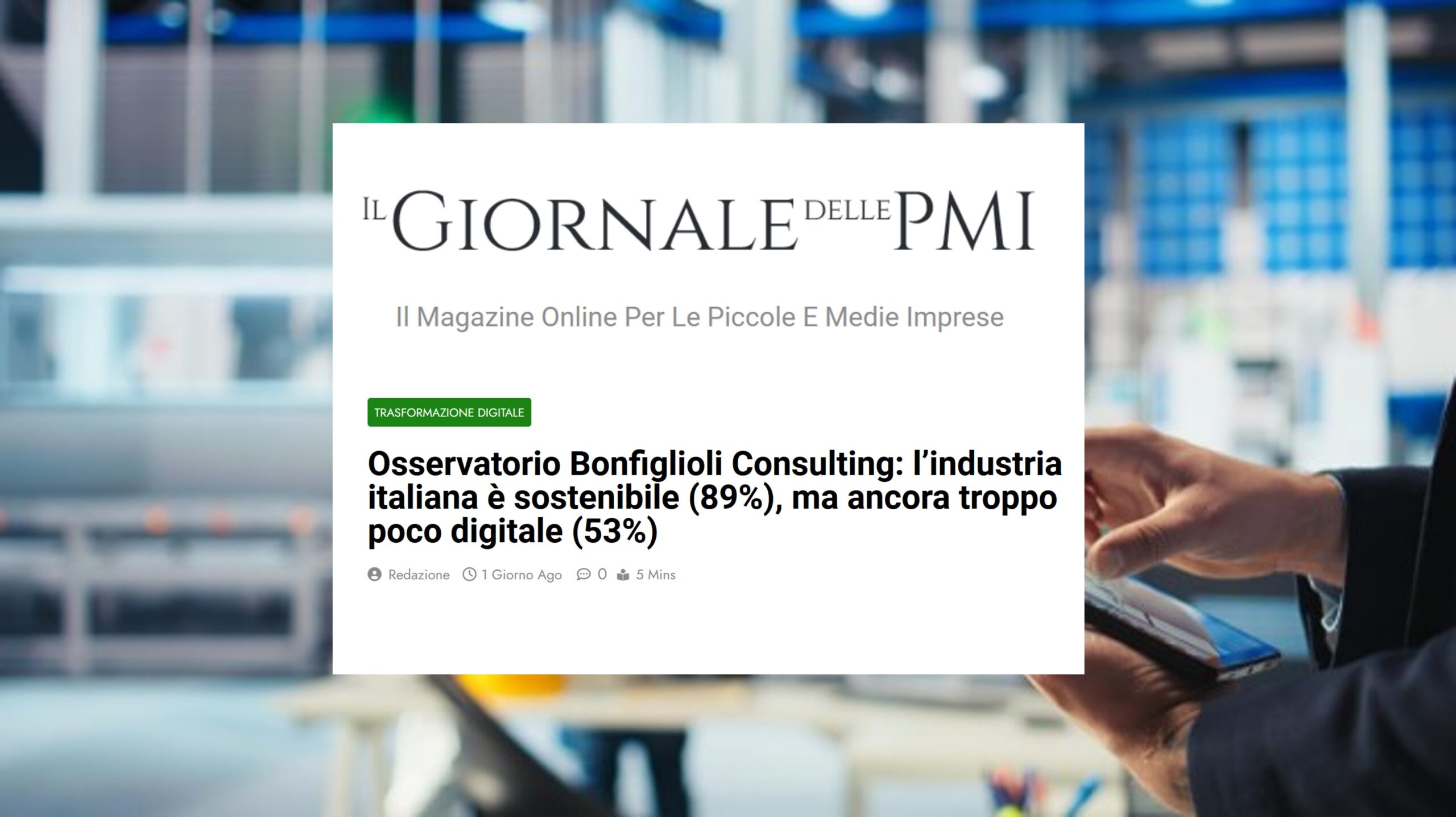 Lo schermo di un computer mostra una Bozza automatica di un articolo de Il Giornale delle PMI sull'industria italiana, la sostenibilità 89 e la digitalizzazione 53, con attrezzature da ufficio sfocate e una persona sullo sfondo.